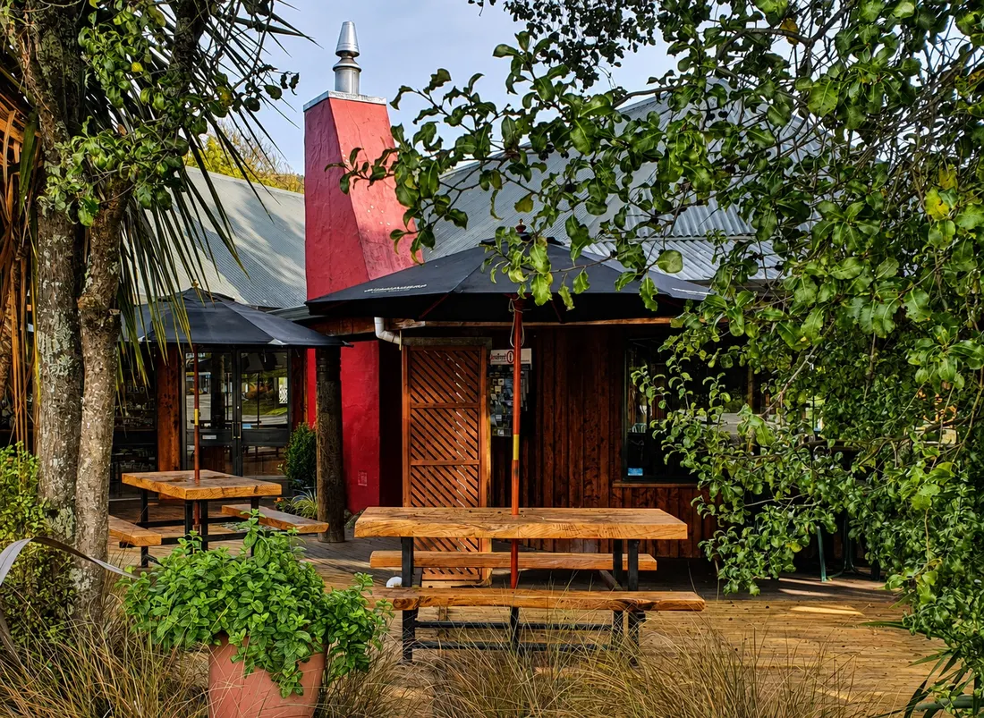 Timber tables beside the red chimney, framed by trees