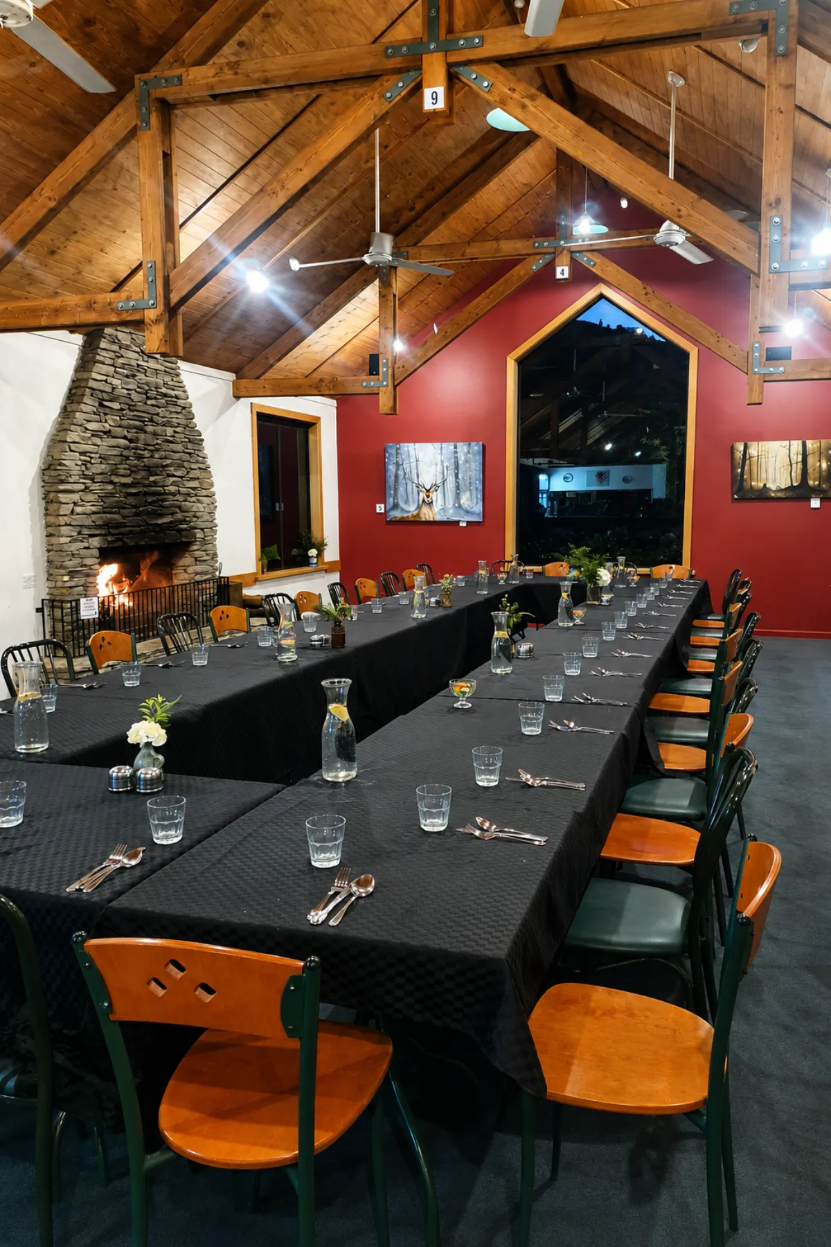 The formal dining area set with long tables beside the stone fireplace